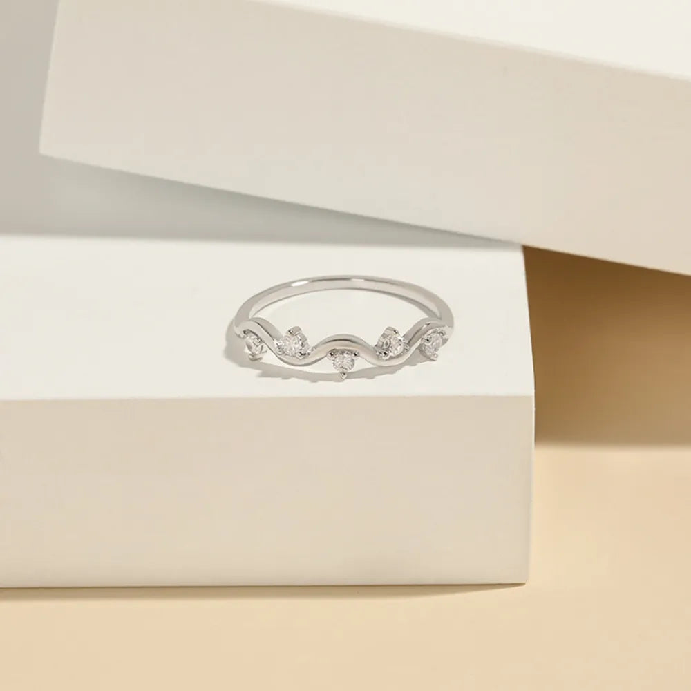 Silver band ring with wavy design and small cubic zirconia stones.