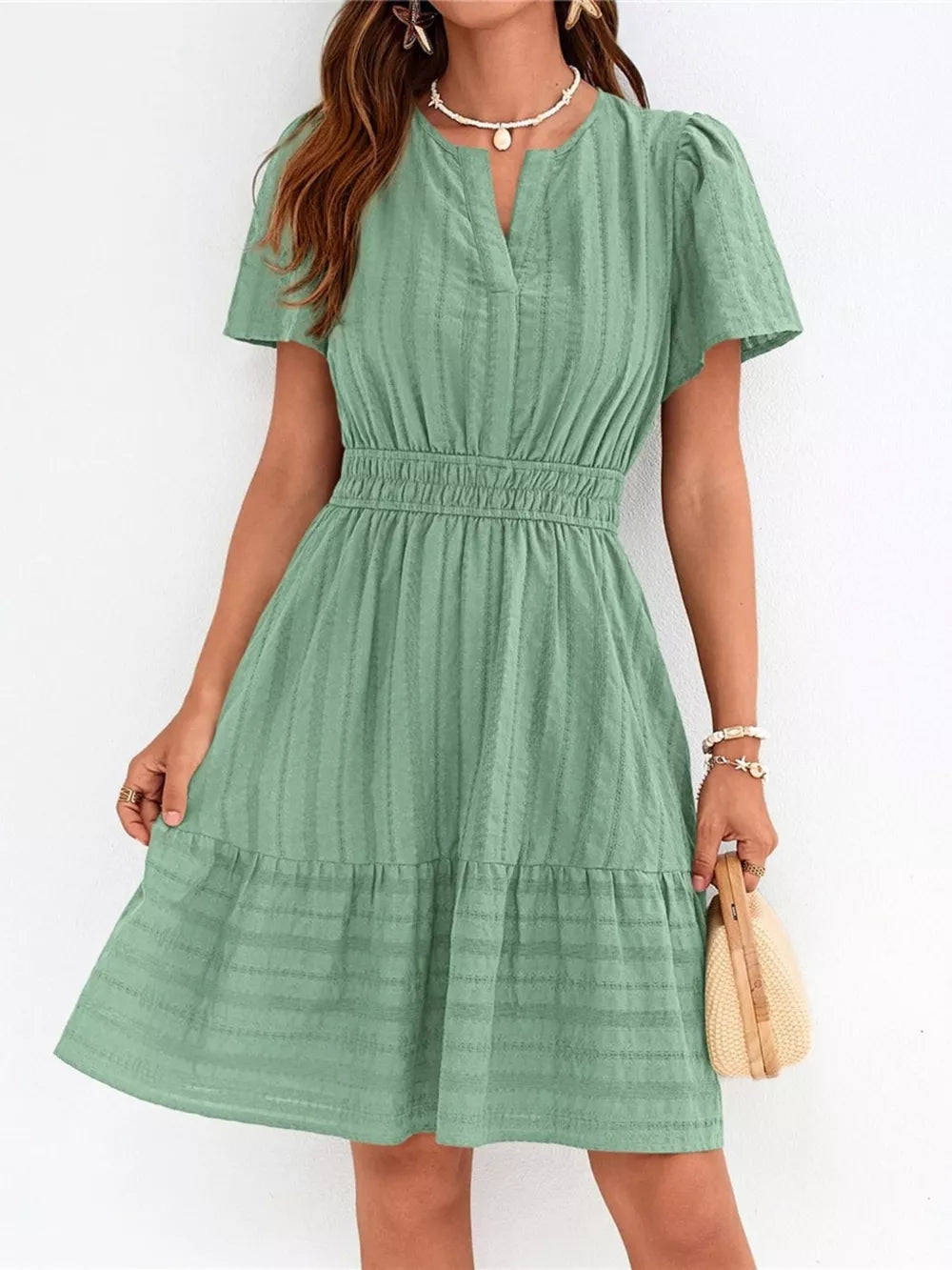 Light green textured V-neck tiered dress with smocked waist and short sleeves.