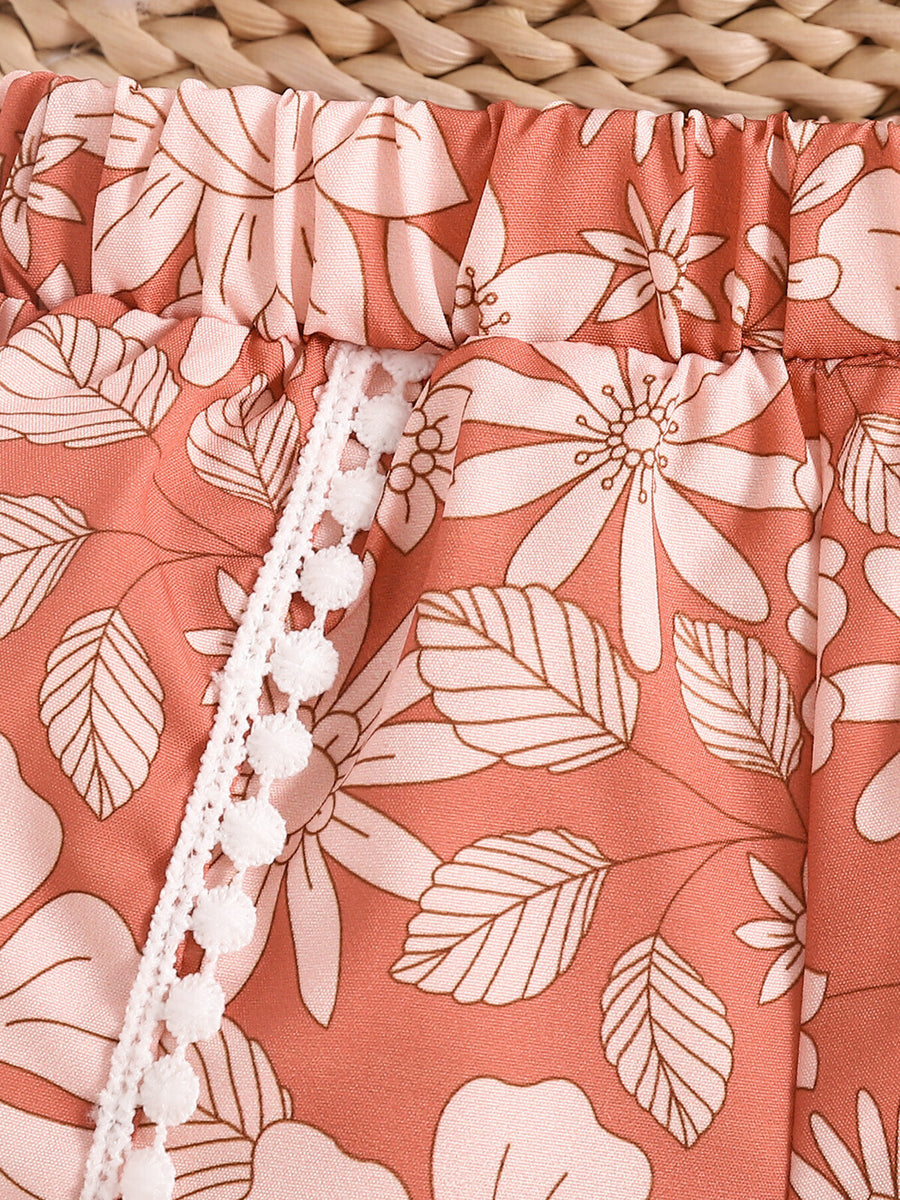Light brown floral print baby shorts with elasticated waist and white pom-pom trim.