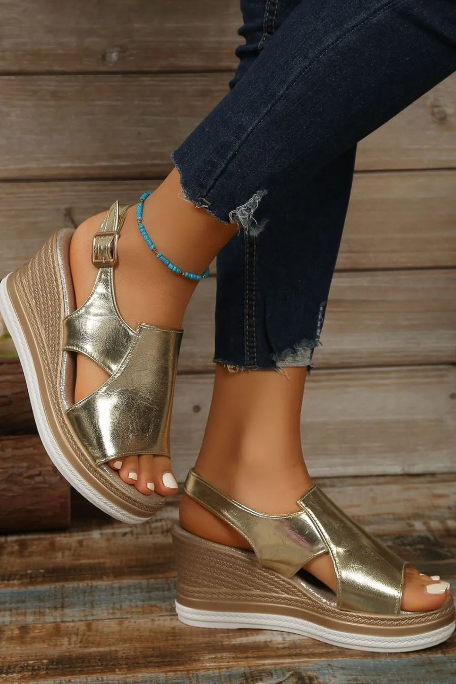 Gold metallic wedge sandals with crisscross detail and ankle strap.
