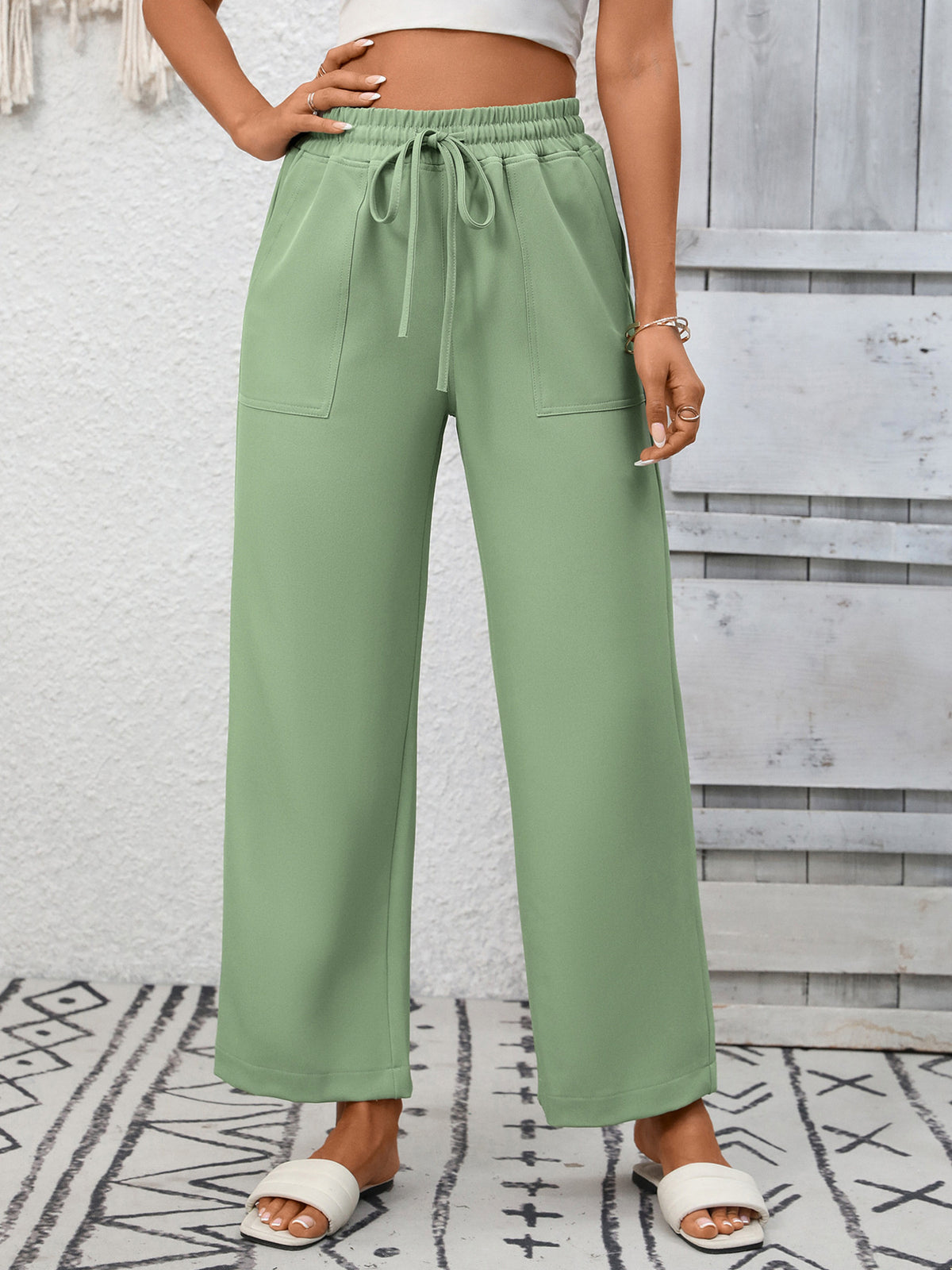 Green drawstring wide-leg pants with pockets, styled casually.