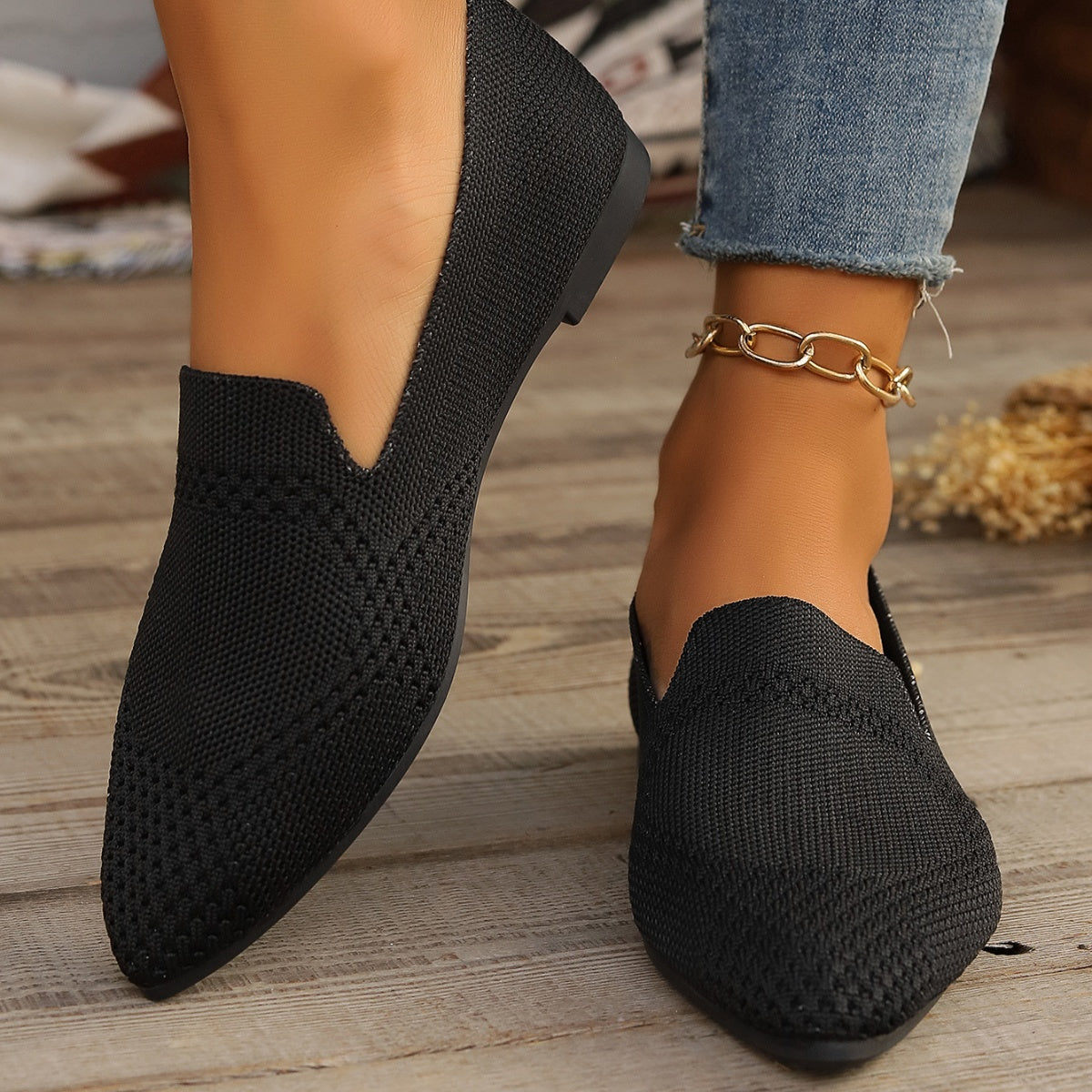 Black breathable pointed-toe knit flats with a low heel and gold chain anklet.