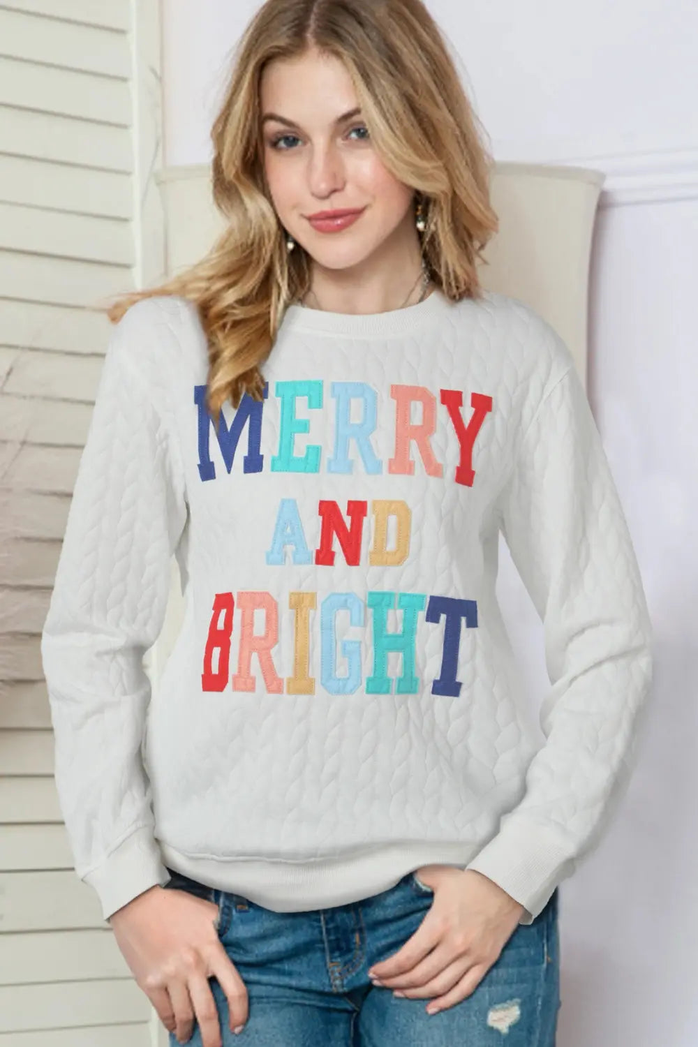 White textured sweatshirt with "Merry and Bright" embroidered in colorful letters