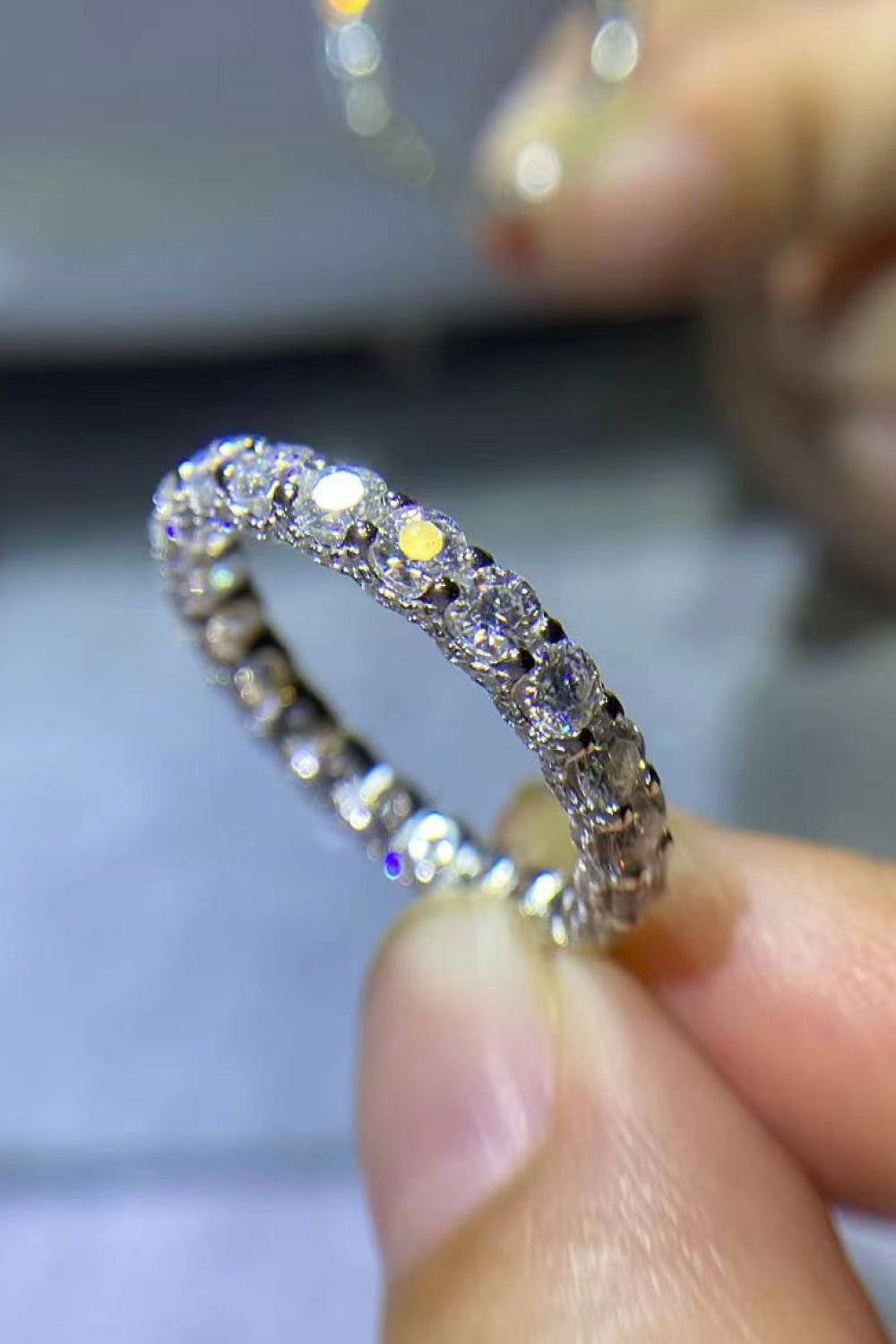 Silver eternity band ring with many small, sparkling moissanite stones.