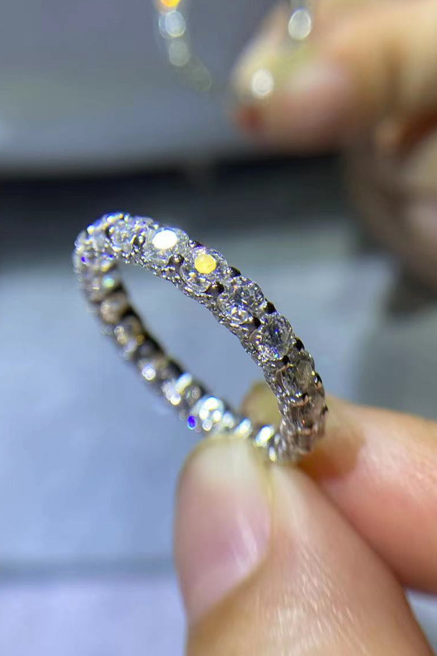Silver eternity band ring with many small, sparkling moissanite stones.