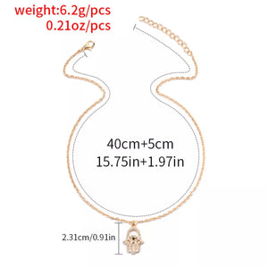 Gold evil eye hamsa pendant necklace with rhinestones and adjustable chain.