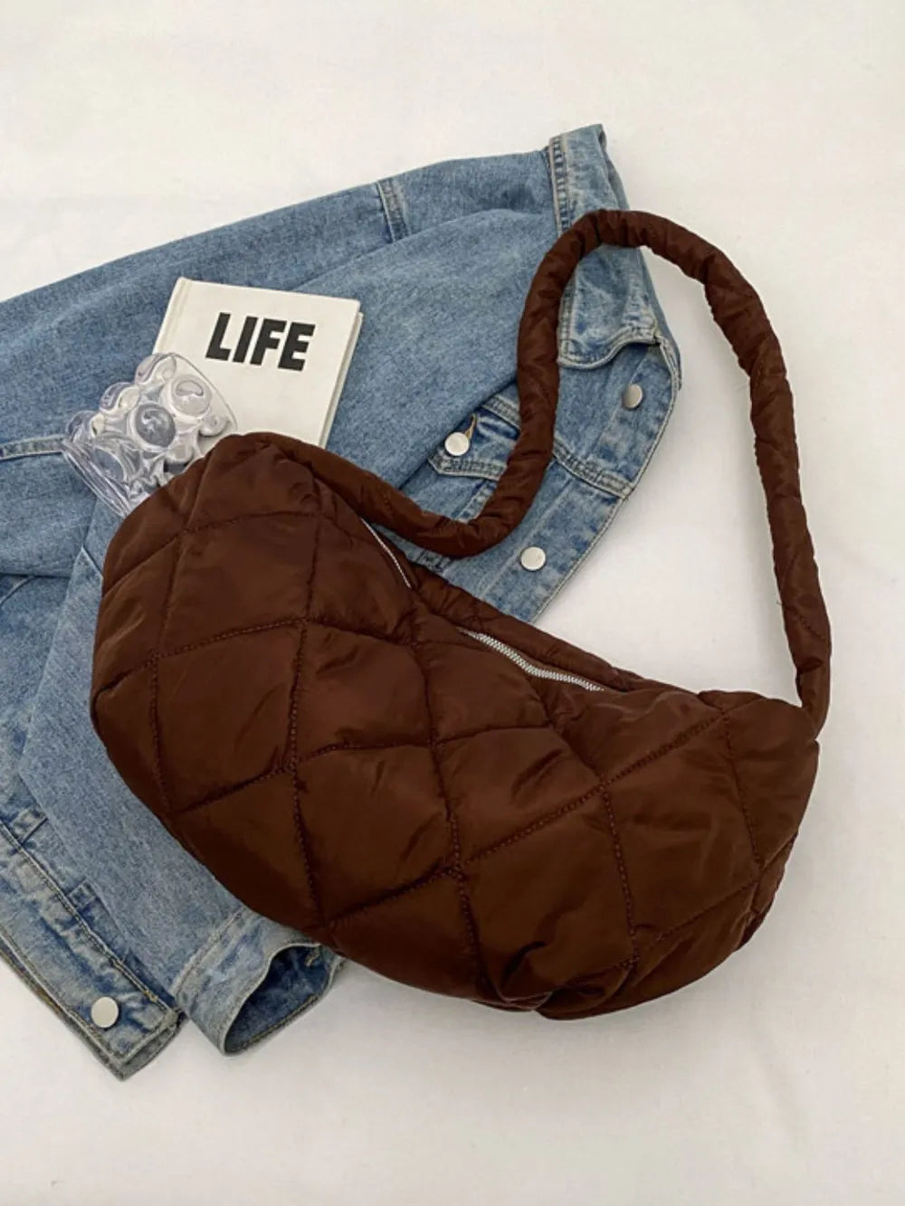 Brown quilted crossbody bag with puffy strap and silver zipper detail.