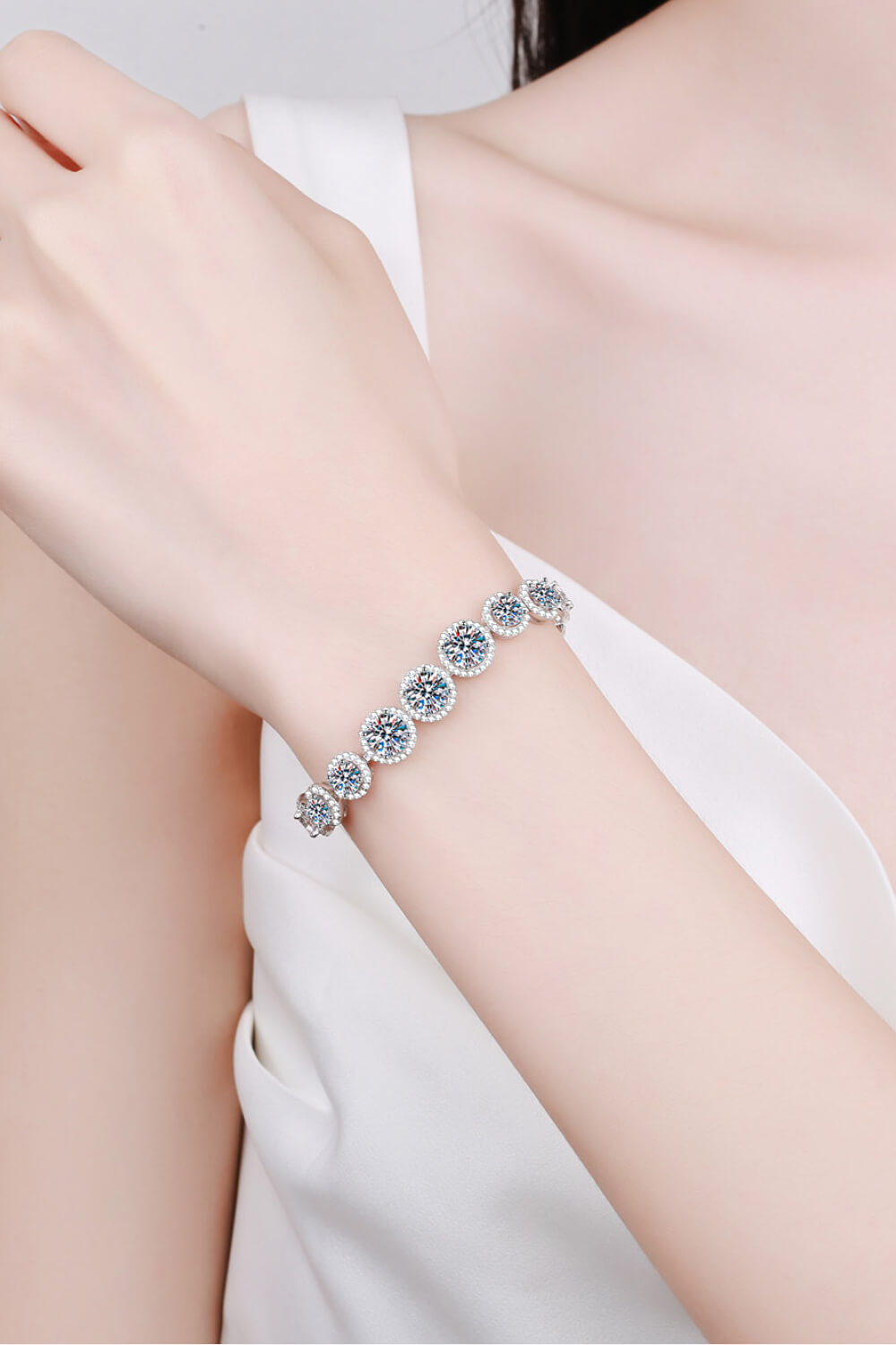Silver halo moissanite tennis bracelet with round-cut stones.