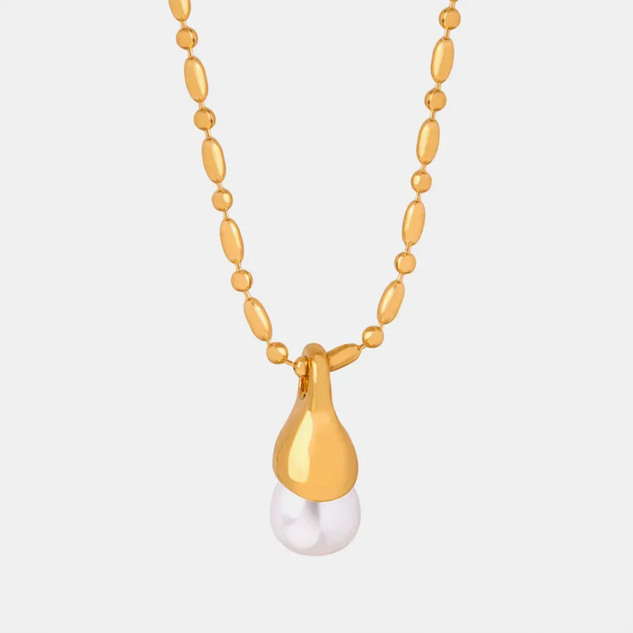 Gold necklace with oval beads and a teardrop pendant holding a pearl.