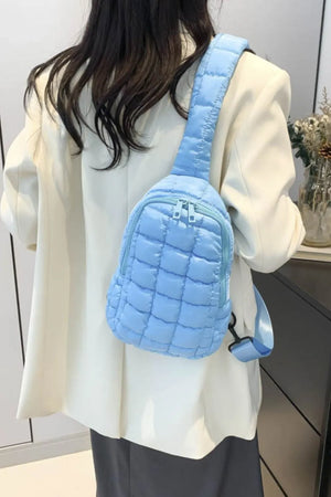 Padded sling bag in pastel blue with quilted texture and top handle.