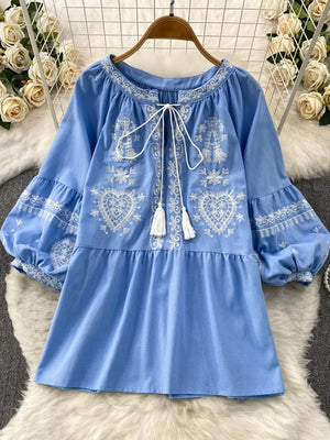 Blue embroidered tie-neck blouse with balloon sleeves and tiered skirt.