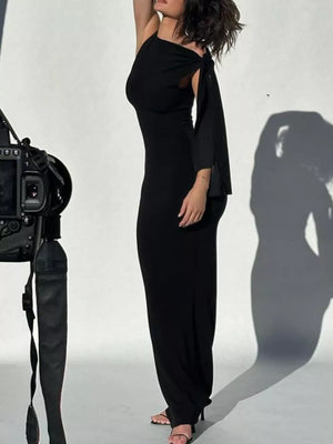 Black asymmetrical draped maxi dress with one shoulder and a bow detail on the sleeve.
