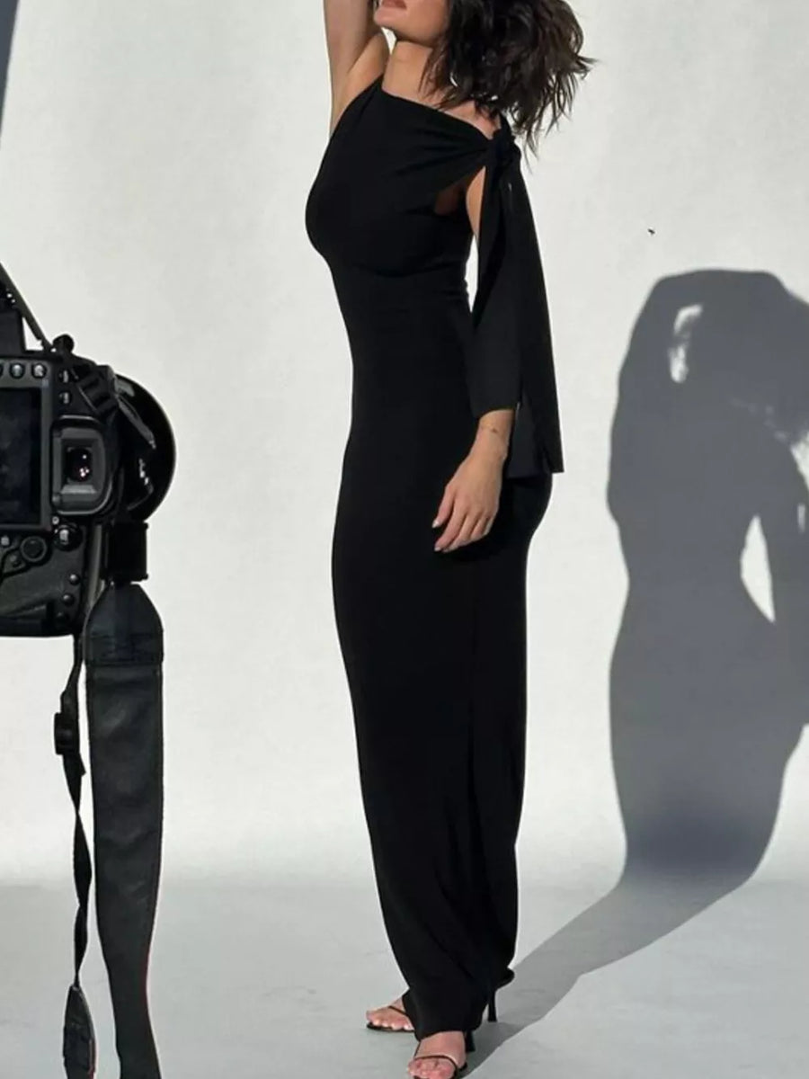 Black asymmetrical draped maxi dress with one shoulder and a bow detail on the sleeve.