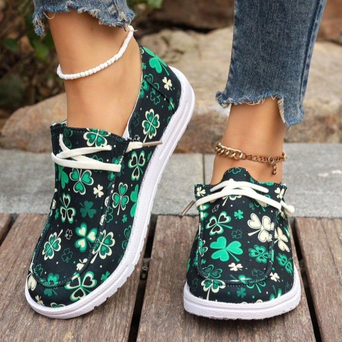 Clover print canvas slip-on sneakers with white decorative laces and white soles.