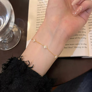 Gold clover charm bracelet with small clear stones on a delicate chain