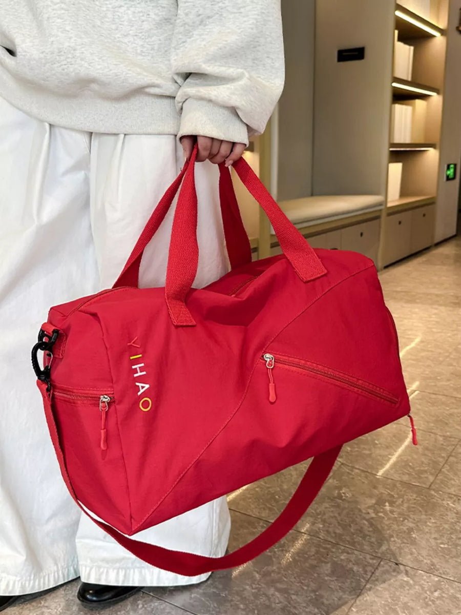 Red duffel bag with embroidered logo, zippered pockets, and dual straps.