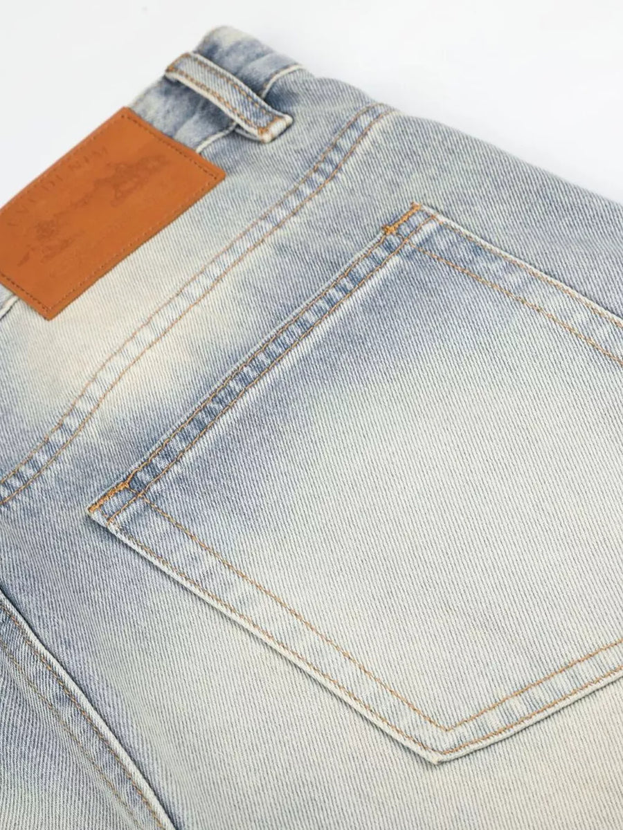 Men's vintage wash wide leg jeans in light blue denim with a brown leather patch.