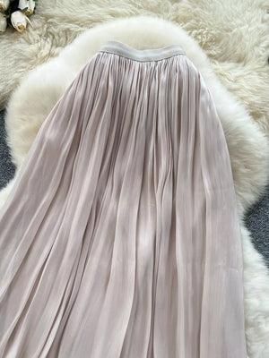 Cream pleated maxi skirt with a flowing, elegant cut.