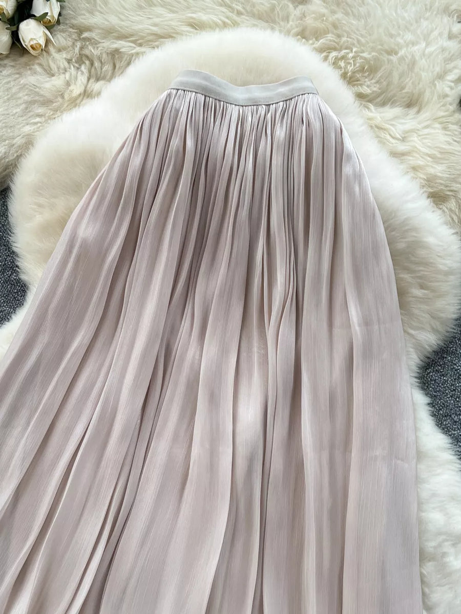 Cream pleated maxi skirt with a flowing, elegant cut.