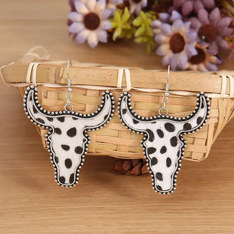 Cow print bull head drop earrings with silver trim and hooks.