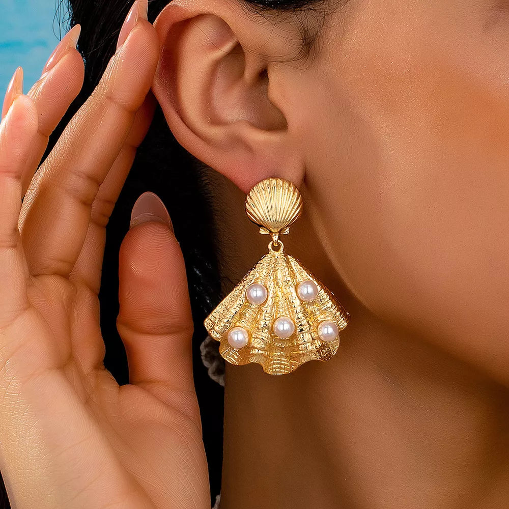 earrings in gold featuring shell design and drop fit
