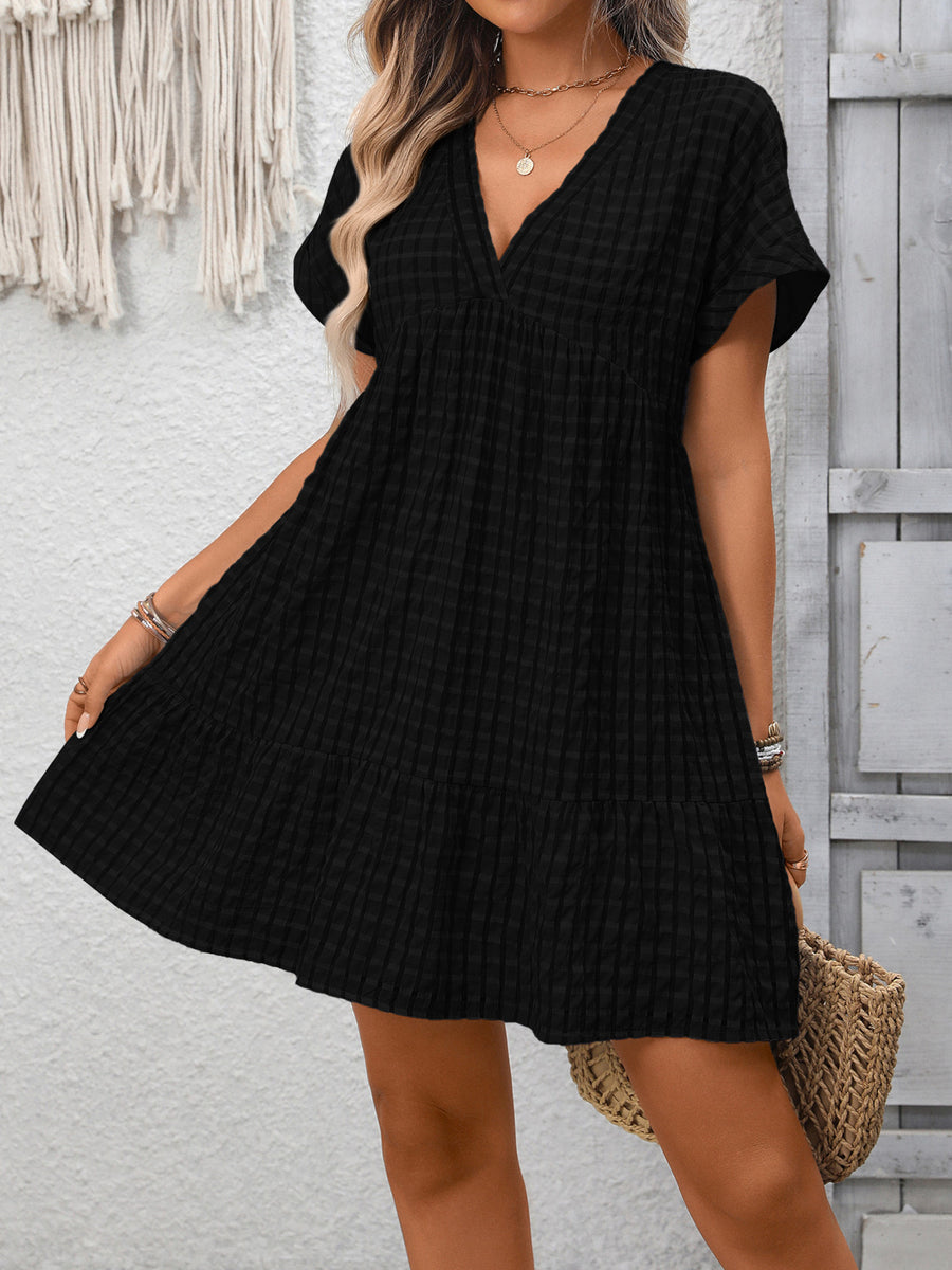 Black plaid V-neck mini dress with short sleeves and tiered hem.