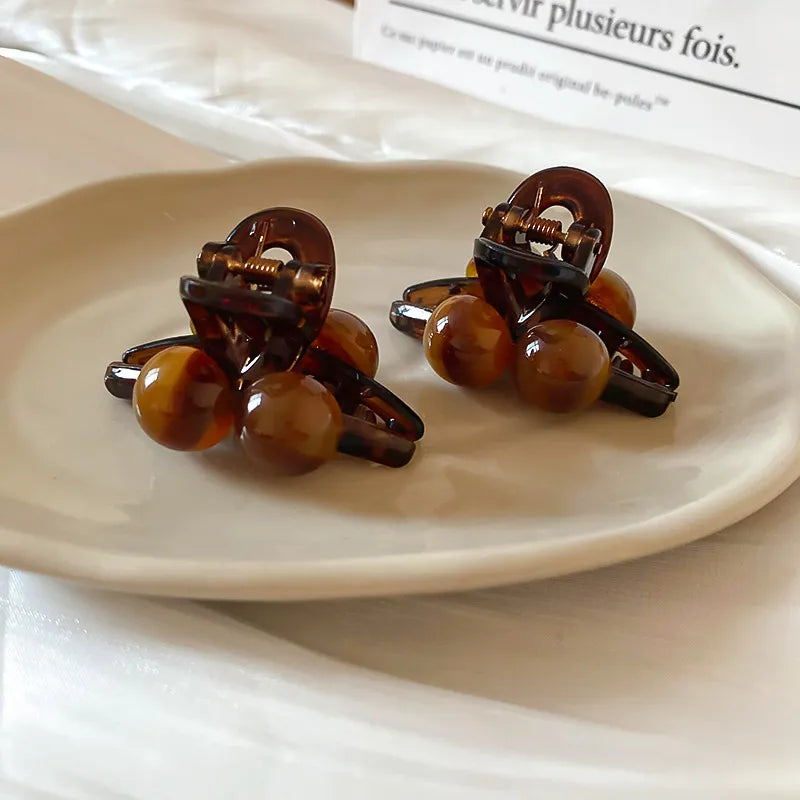 Brown resin orb hair claws with acrylic tortoise shell pattern.