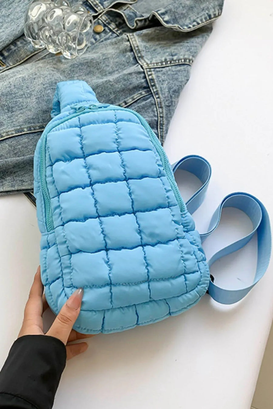 Padded sling bag in Pastel Blue with quilted pattern and top handle.