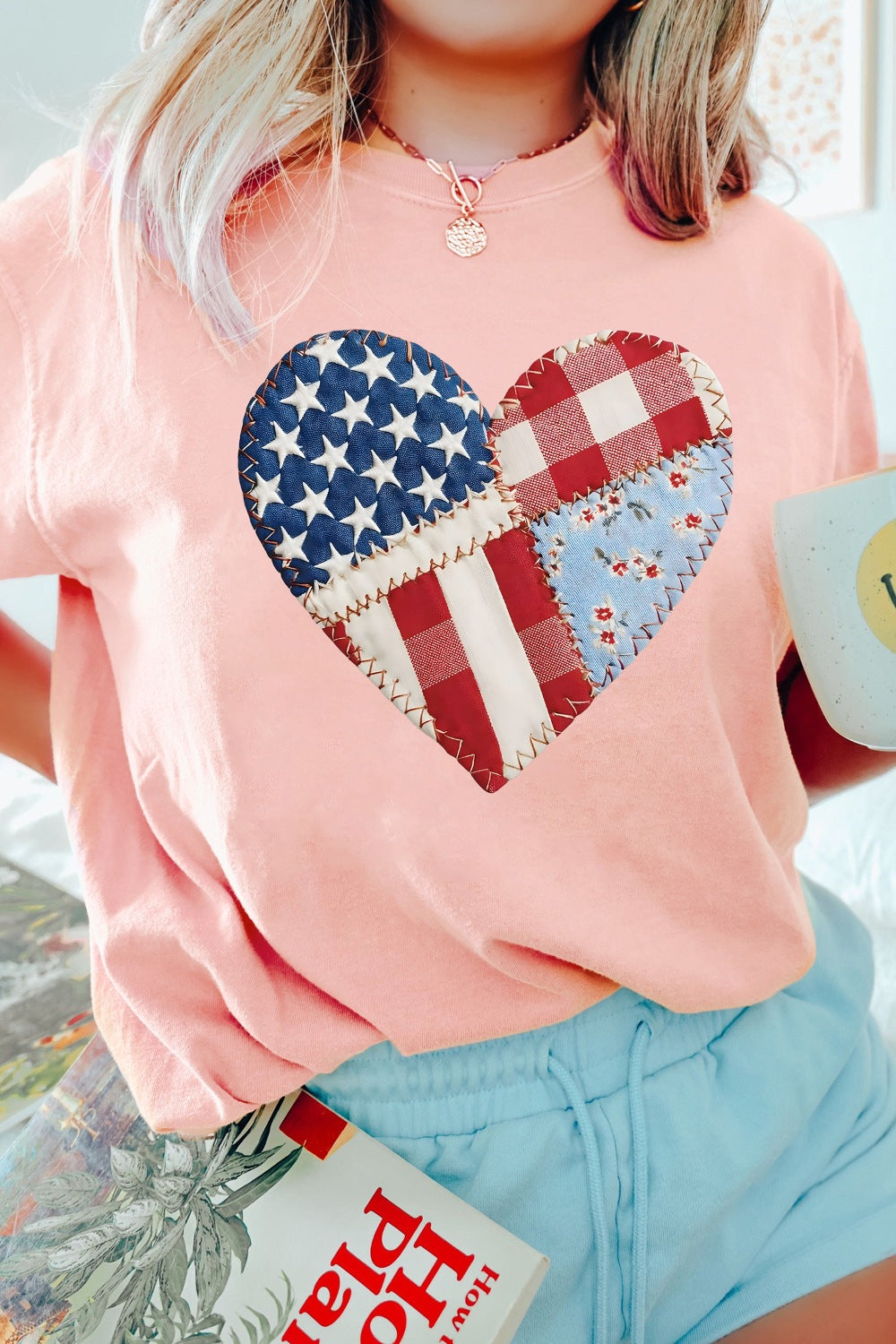 Pink t-shirt with a patriotic heart graphic made of patchwork American flag and gingham patterns.