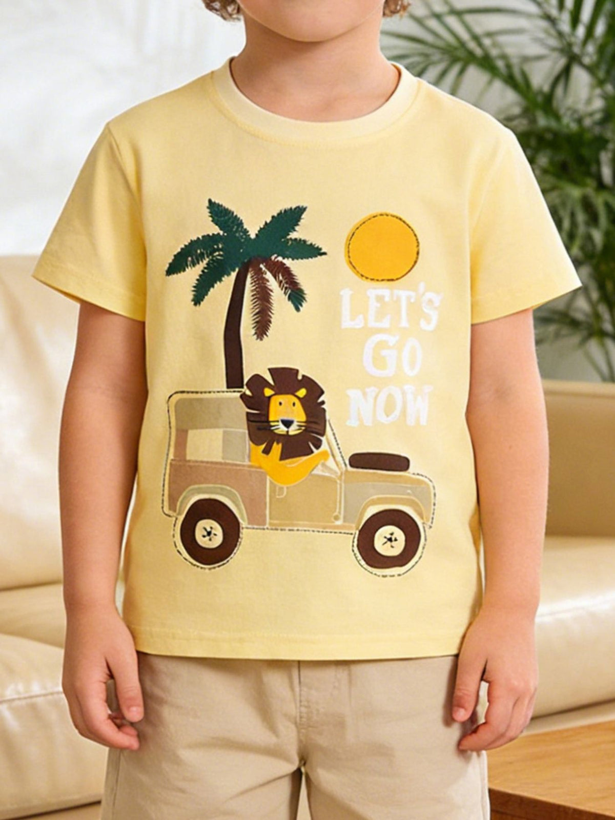 Yellow cotton t-shirt with appliqued lion in a safari jeep, palm tree, sun, and text.