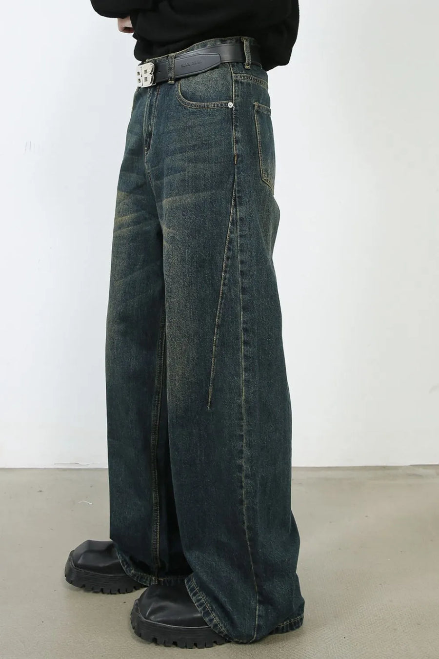 Faded dark denim wide-leg trousers with a relaxed fit and visible stitching detail.