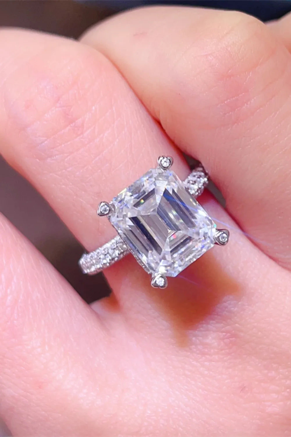 Emerald cut moissanite ring with pave band in silver.