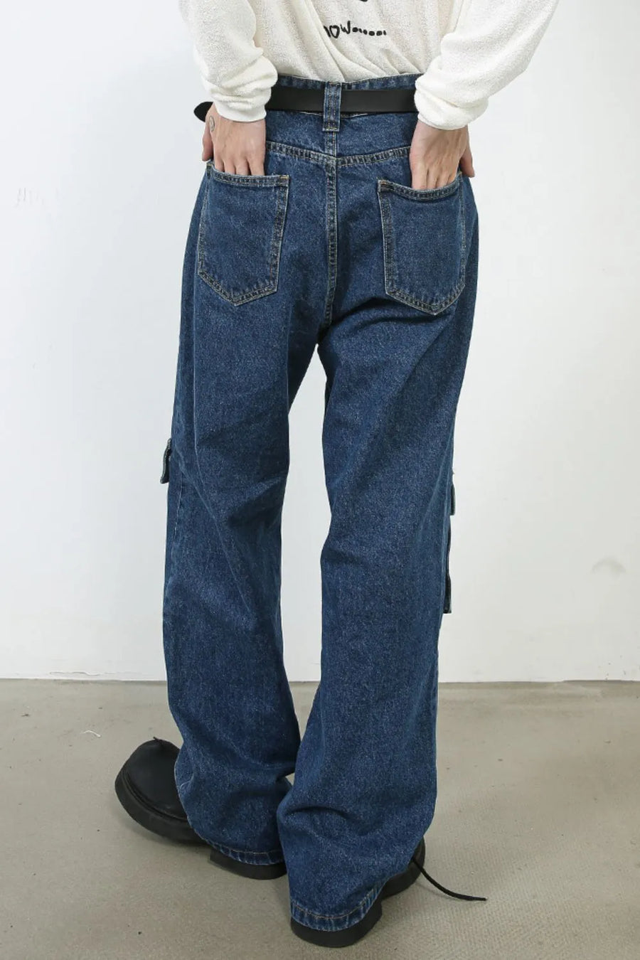 Medium wash denim cargo pants with buckle pocket detail and wide leg cut.