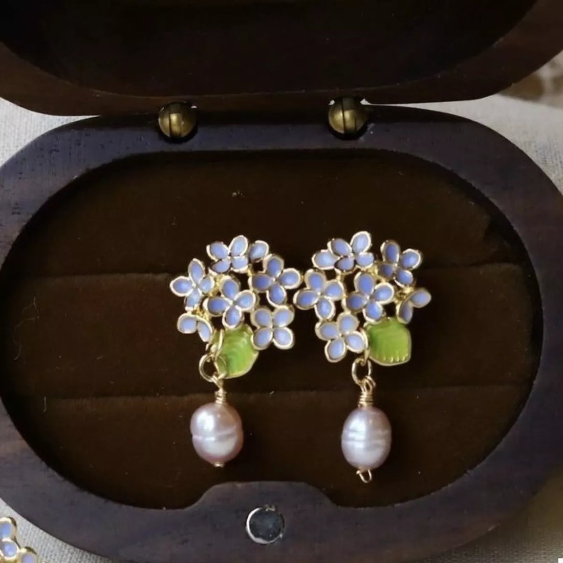 Floral pearl drop earrings with light blue flowers and pink pearls.