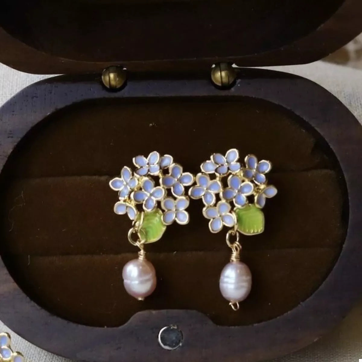 Floral pearl drop earrings with light blue flowers and pink pearls.