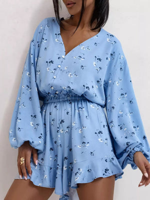 Blue floral cotton romper with V-neck, cinched waist, balloon sleeves, and ruffled hem.