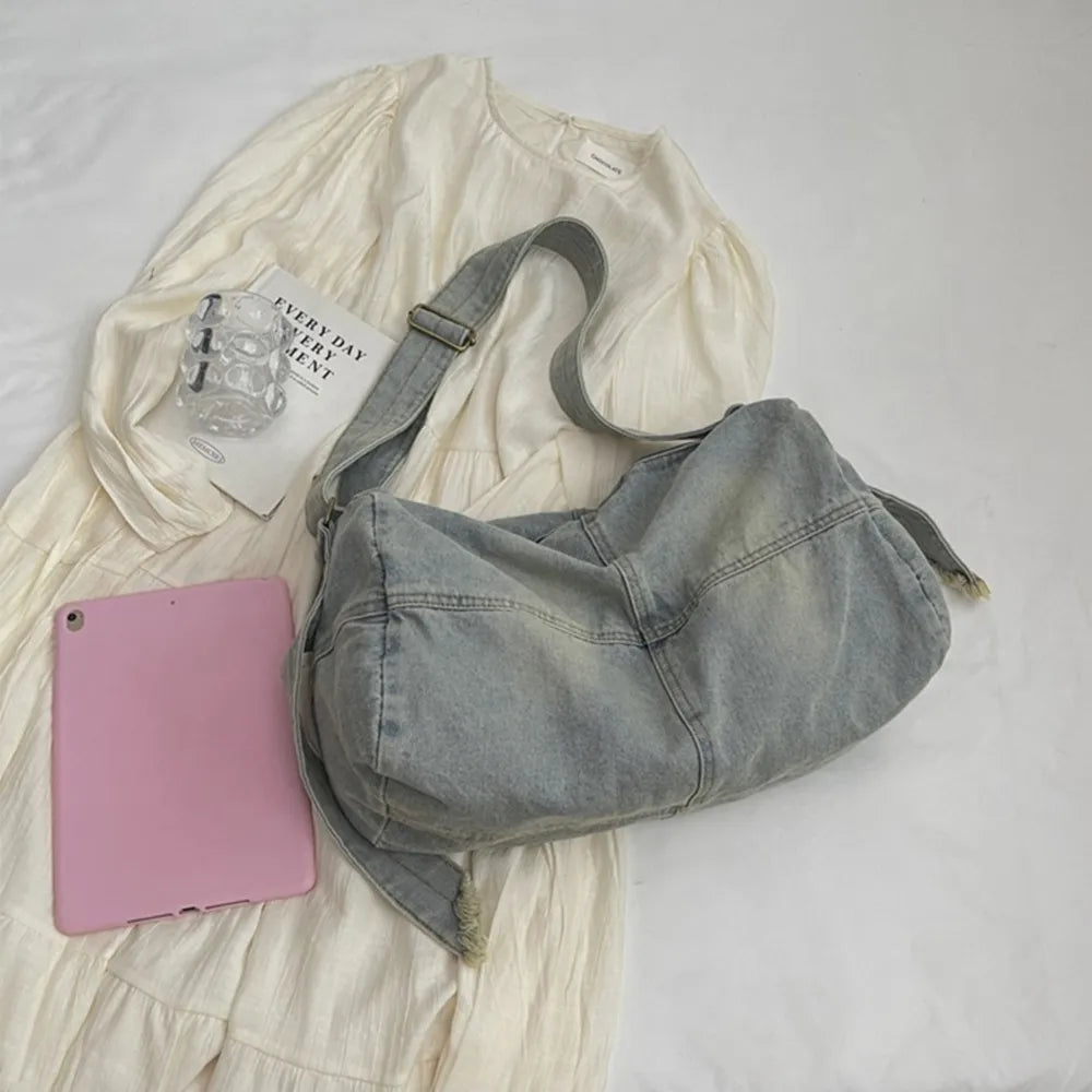 Washed denim hobo bag in light blue with frayed edges and adjustable strap.