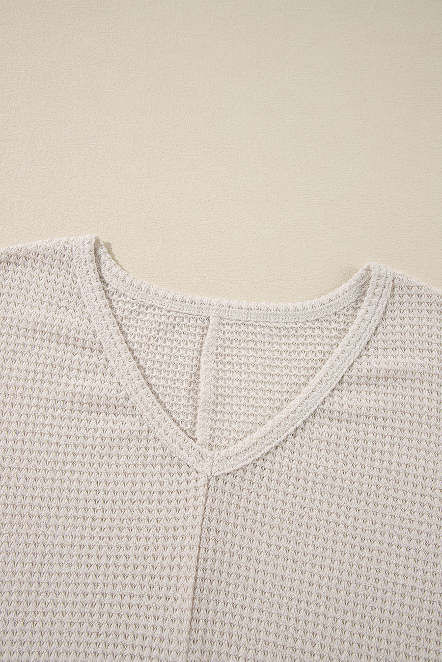 Beige waffle knit V-neck top with a subtle slit detail at the neckline.