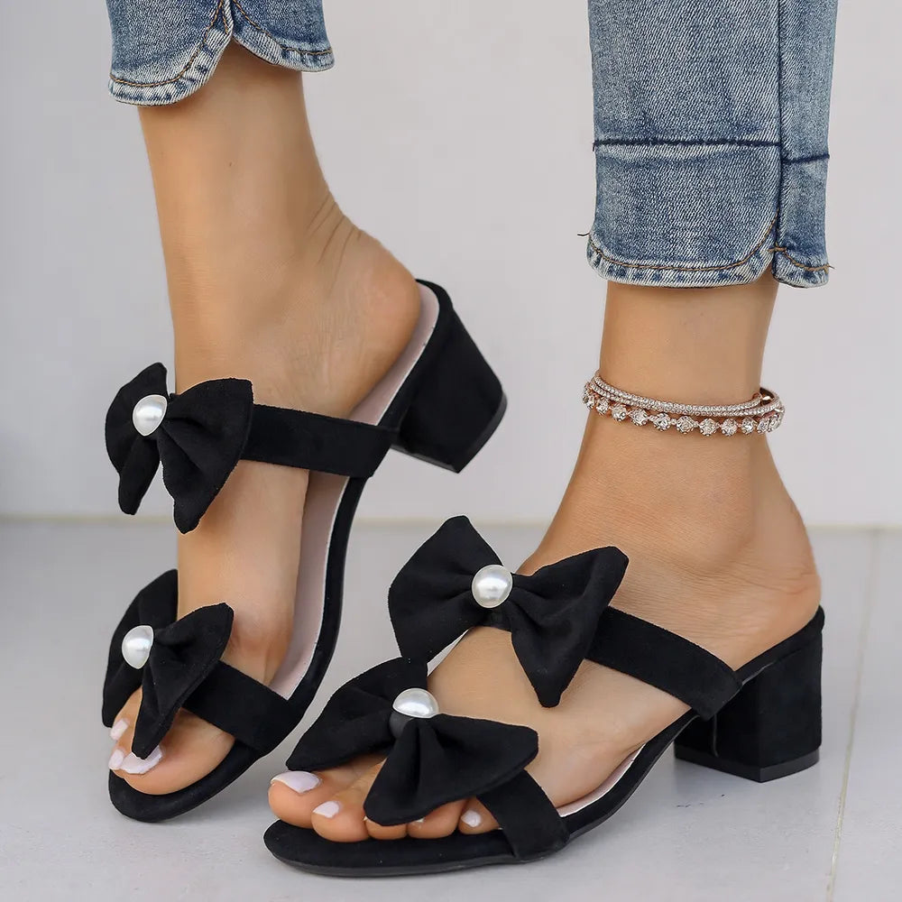 Black bow block heel mules with pearl embellishments.