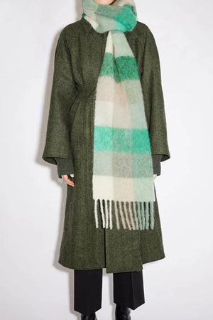 Checked plaid fringed winter wrap scarf in white, green, and beige grid pattern with fringe detail.