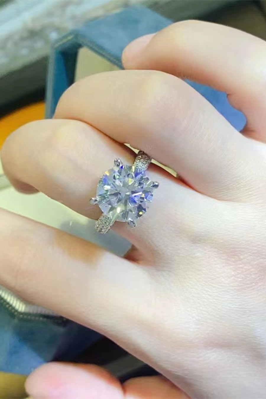 Silver pavé band round moissanite solitaire ring with a large center stone.