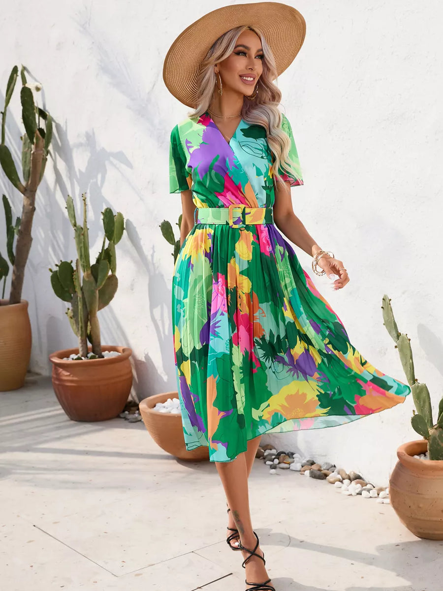 Tropical pleated midi dress with belt in vibrant floral print, featuring a wrap neckline and short sleeves.