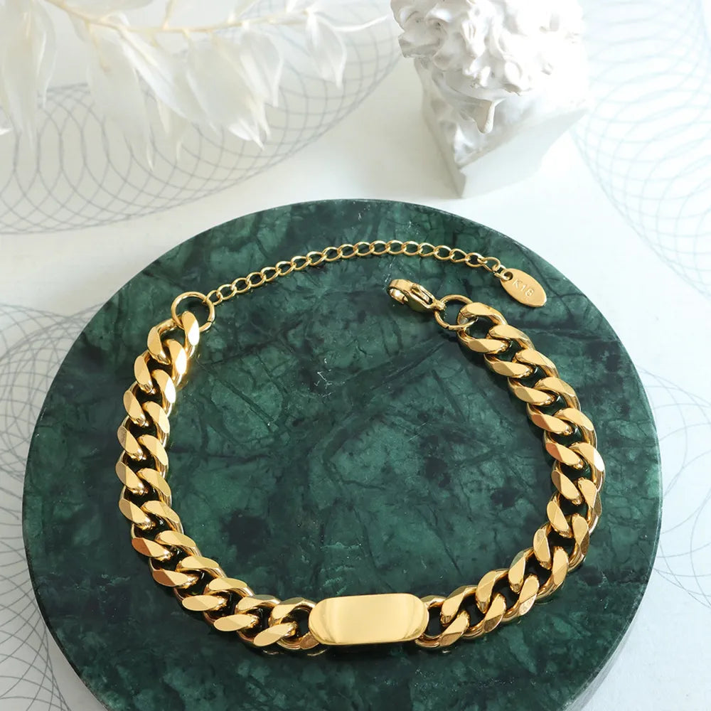 Gold chunky curb chain ID bracelet with oval plate and adjustable clasp.
