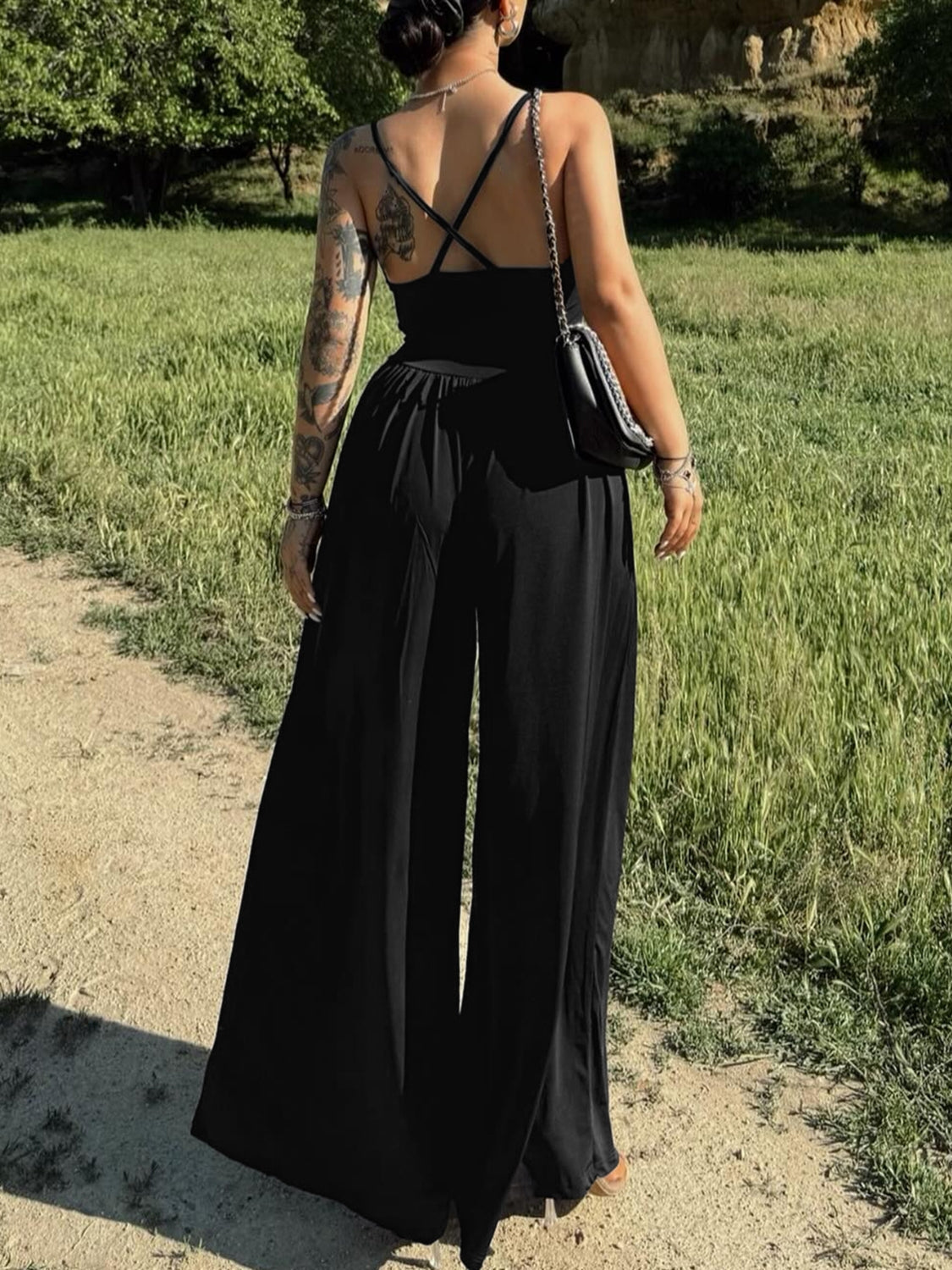 Black crossover back palazzo jumpsuit with wide legs and spaghetti straps.