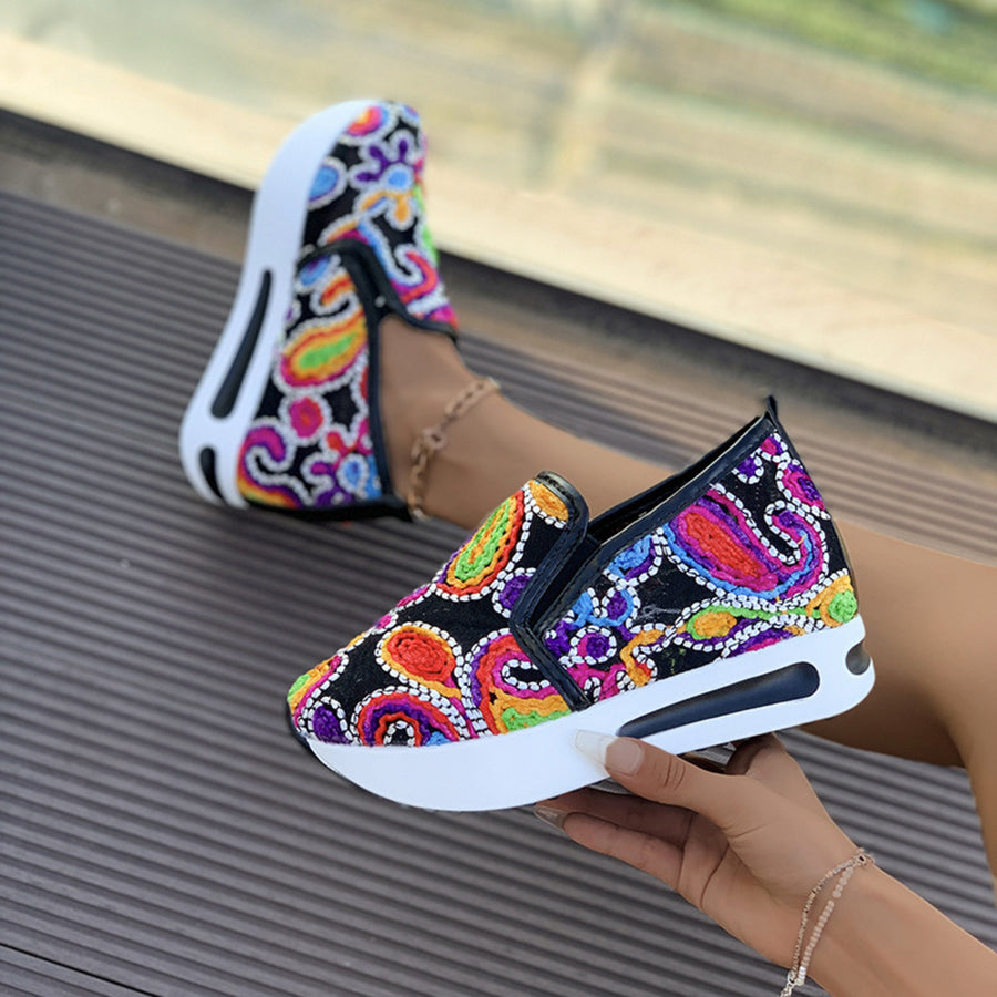Vibrant slip-on platform sneakers with colorful paisley embroidery and a chunky white sole.