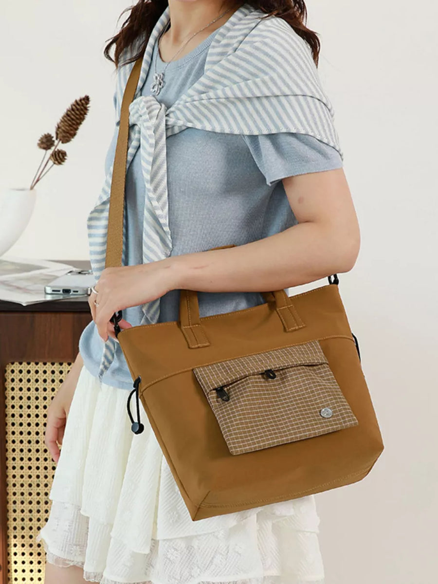 Brown nylon crossbody bag with plaid pocket detail and adjustable strap.