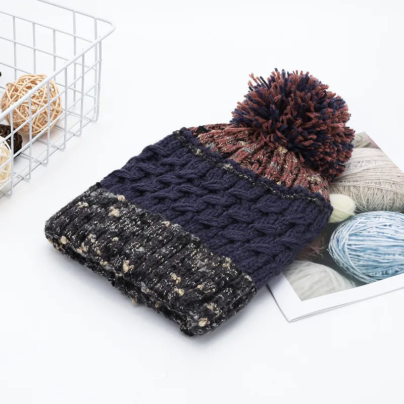 Navy cable knit beanie with textured band and multicolor pompom.