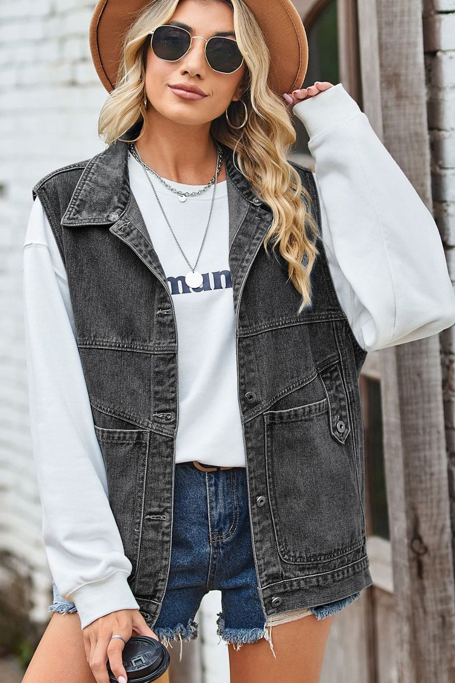 Dark denim vest with button front and chest pockets, worn over a white sweatshirt.