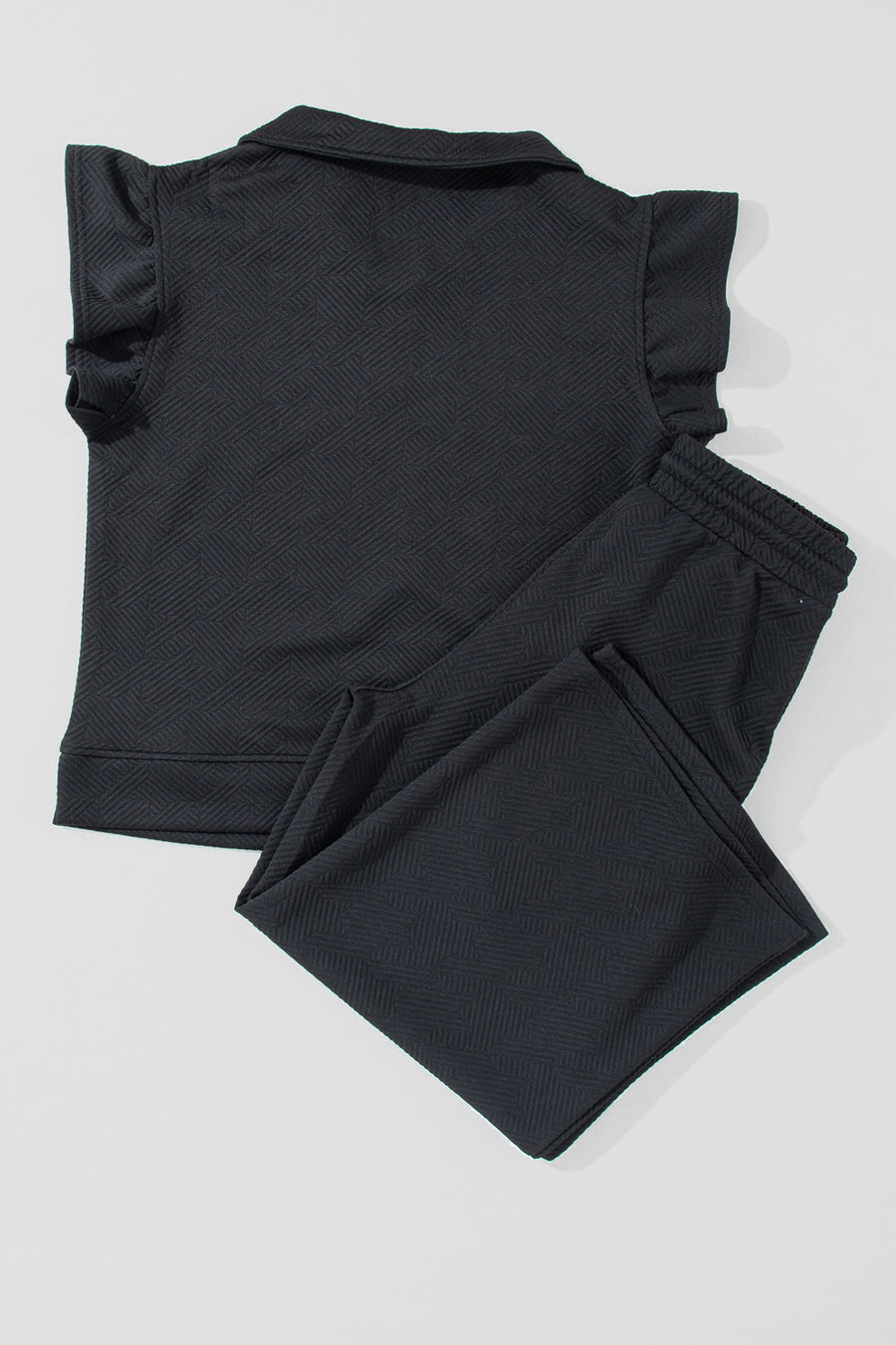 Black textured loungewear set with ruffle sleeve zip-up top and drawstring pants.