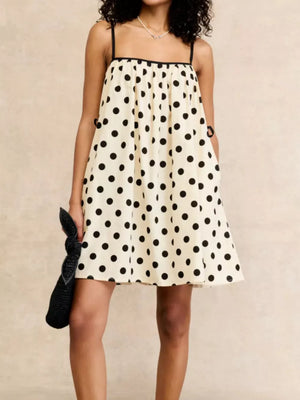 Cream polka dot mini dress with black trim, spaghetti straps, and square neckline.